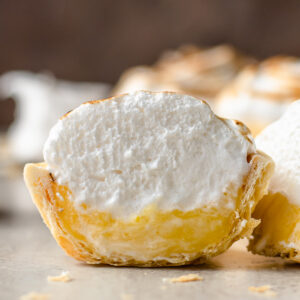 Mini Lemon Meringue Pie cut in half to see lemon curd, meringue, and a flaky pie crust shell.