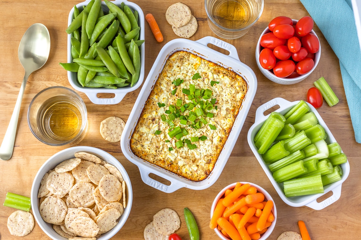 Feta & Onion Hot Dip surrounded by veggies, crackers, and wine.