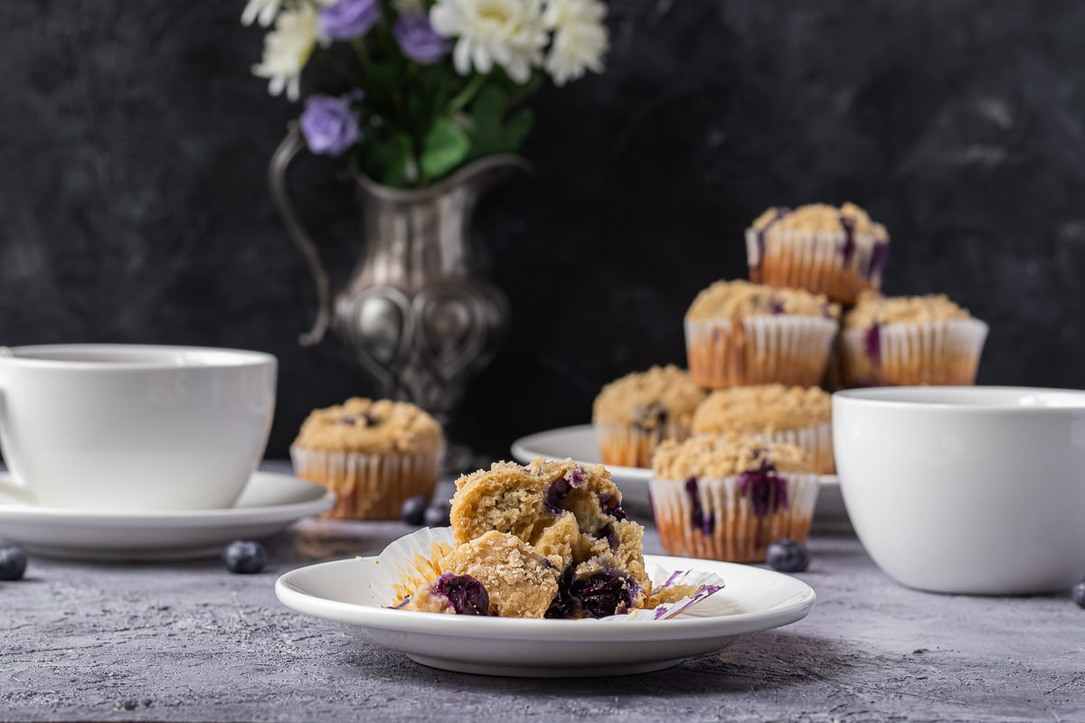 Interior shot of Blueberry Earl Grey Muffins with Streusel. Stack of muffins and tea in the background.