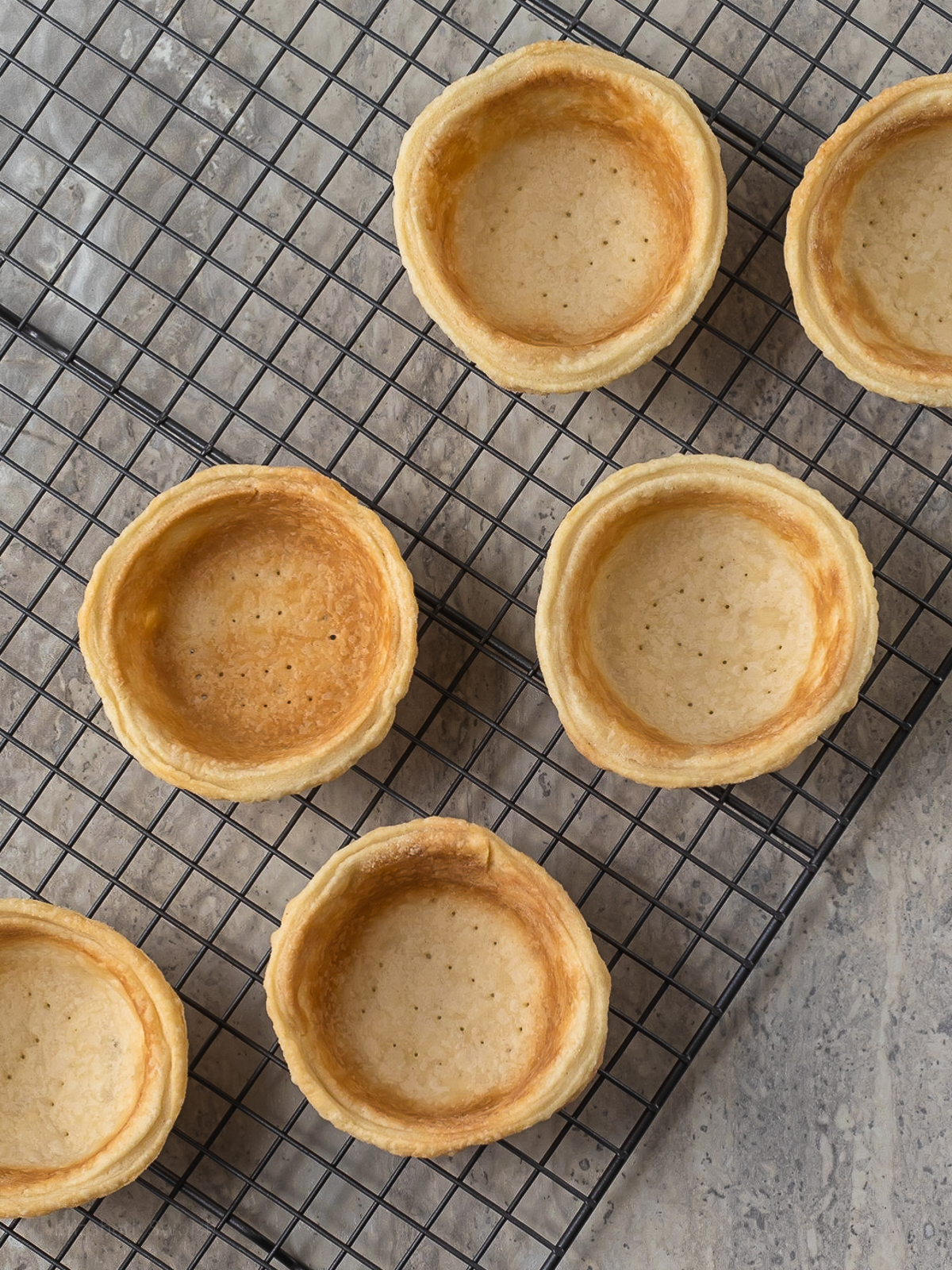 Mini pie crust shells on a cooling rack ready to fill.