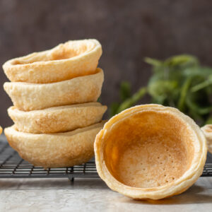 Stack of Mini Pie Crust Shells with one flipped to see the browned and flaky inside.