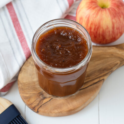 Apple Butter BBQ Sauce in a jar with a pastry brush and apple to show the major flavor.