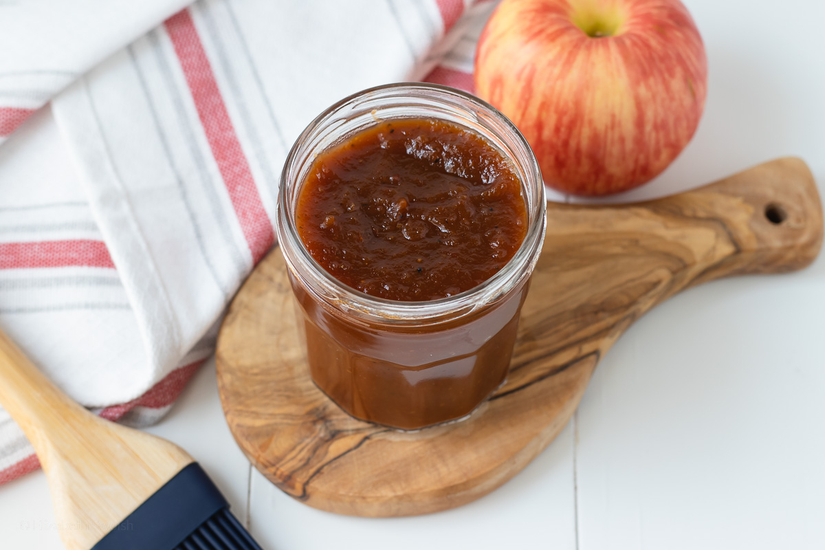 Apple Butter BBQ Sauce in a jar with a pastry brush and apple to show the major flavor.