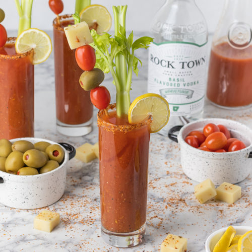Basil Bloody Mary rurrounded by toppings and Tajin