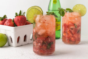 Strawberry Mojito Mocktail in a glass garnished with lime slices and mint leaves.