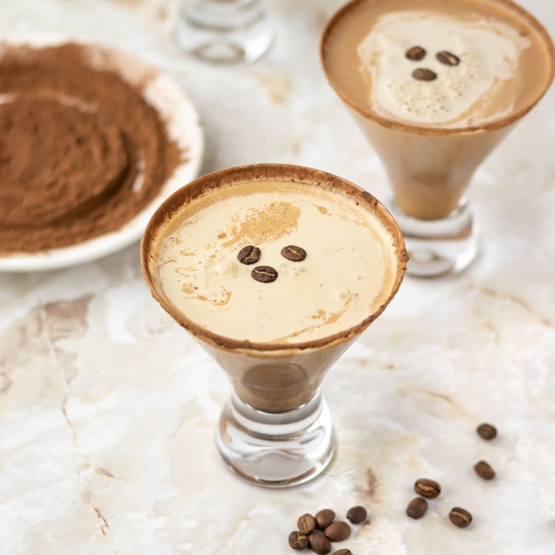 Espresso Martini Mocktails in glasses topped with coffee beans and cocoa powder