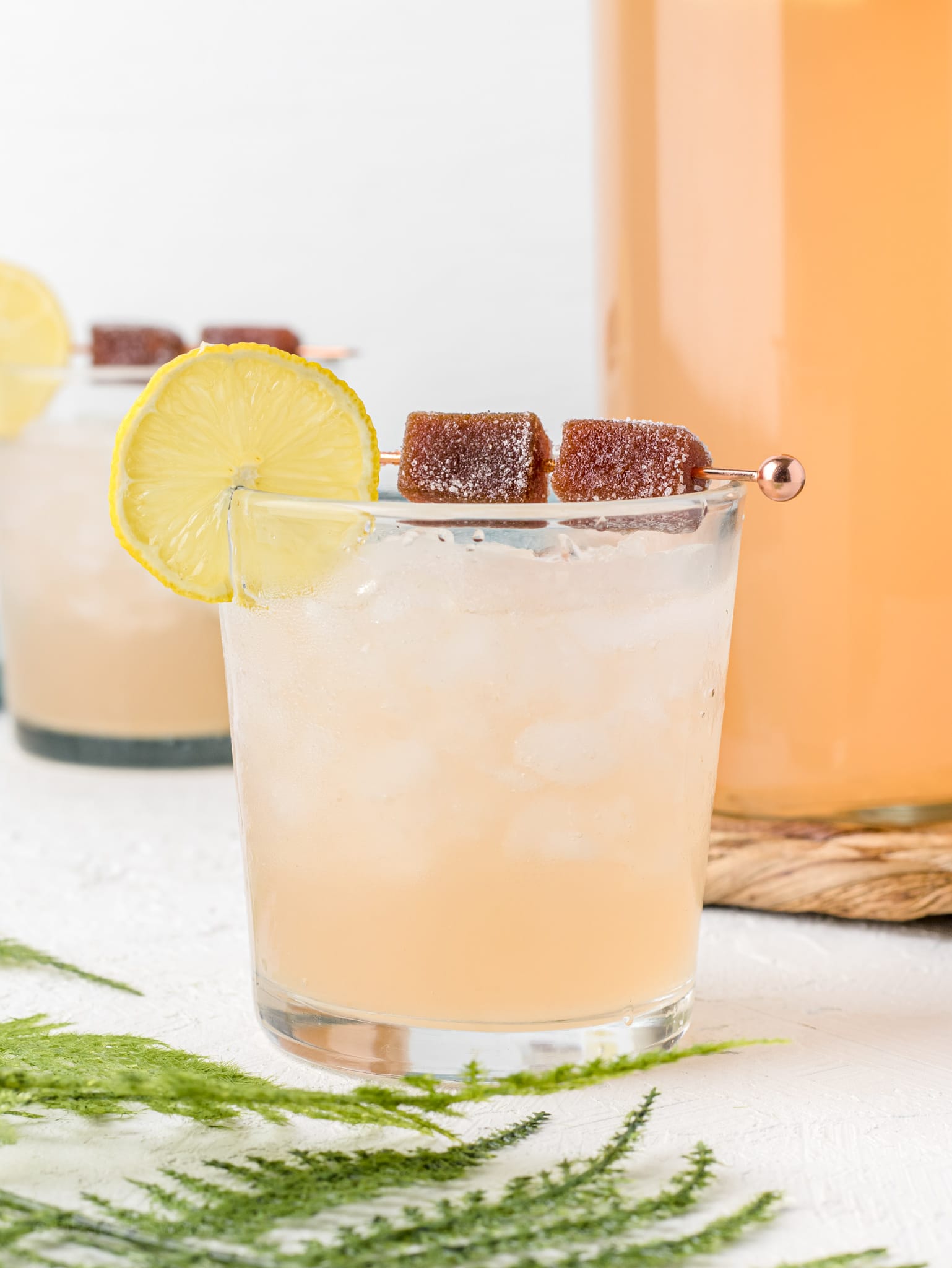 Guava Lemonade Fizz in glasses garnished with a lemon slice and candied guava paste on skewers.