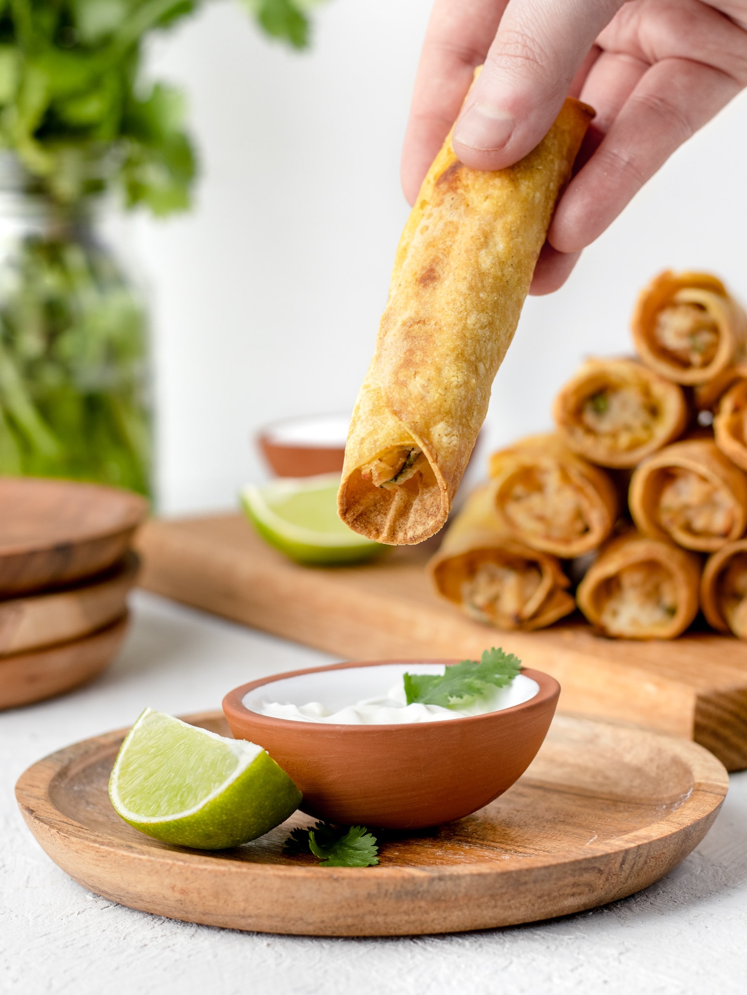 Taquito being dipped in sour cream.