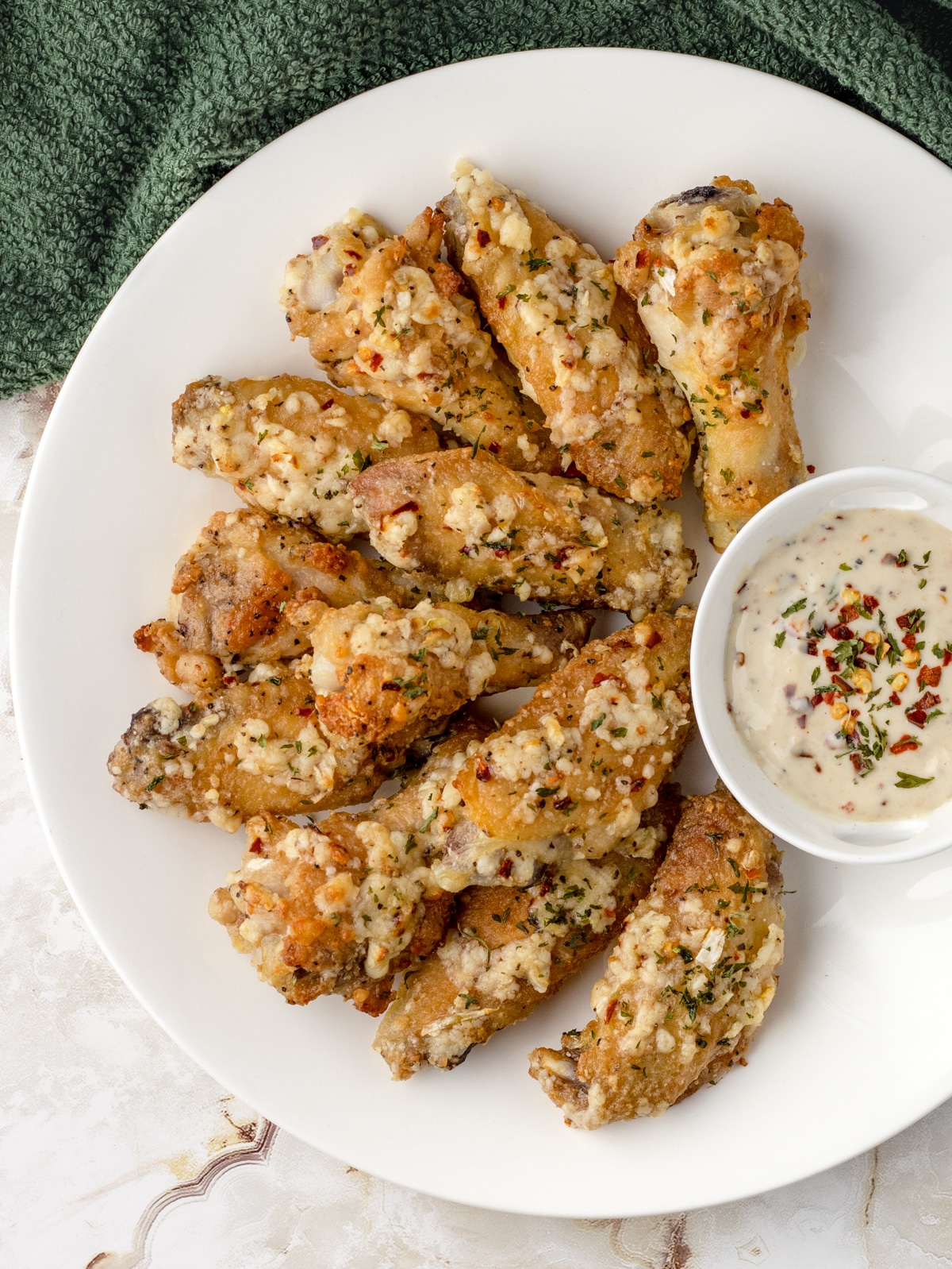 Plate of garlic butter parmesan wings and spicy Caesar dressing.
