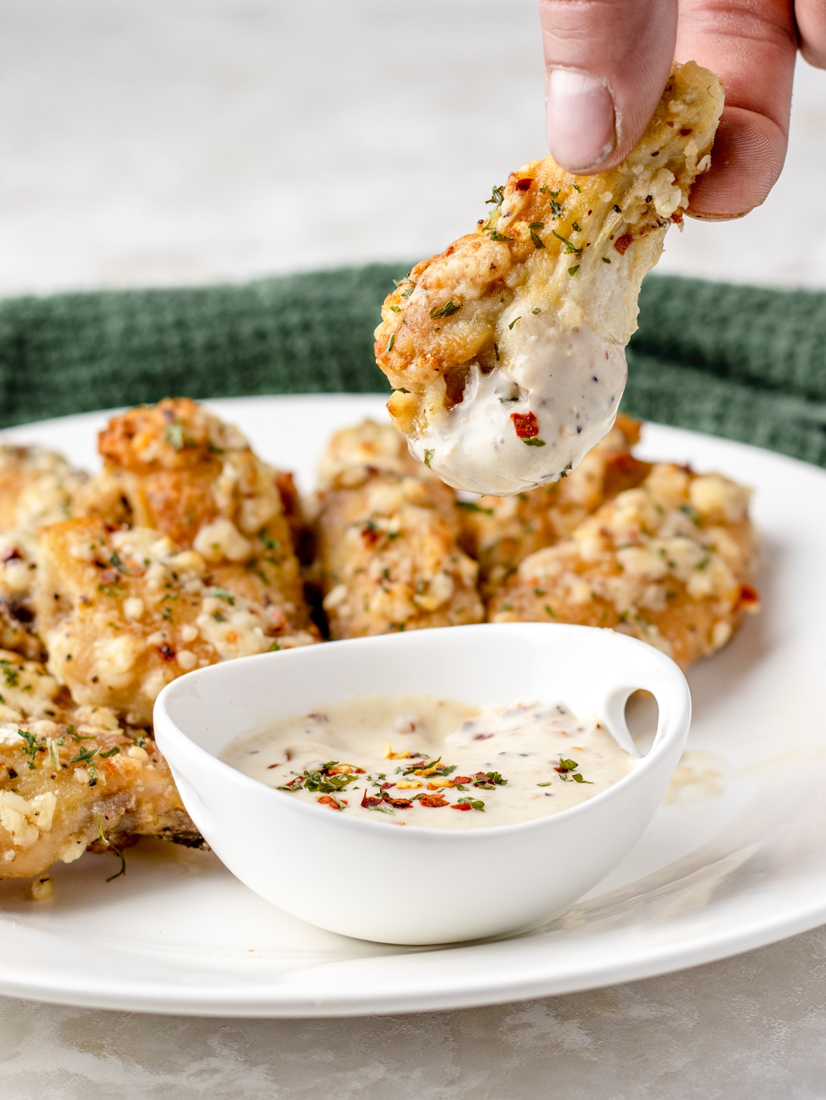 Dipping Garlic Butter Parmesan Wings in sauce