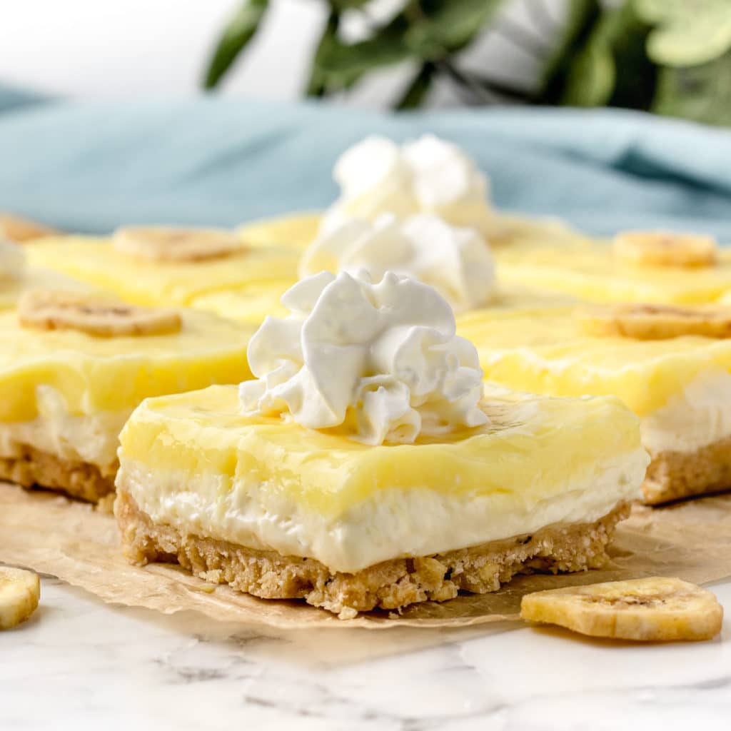 Banana pudding cheesecake bars topped with whipped cream.