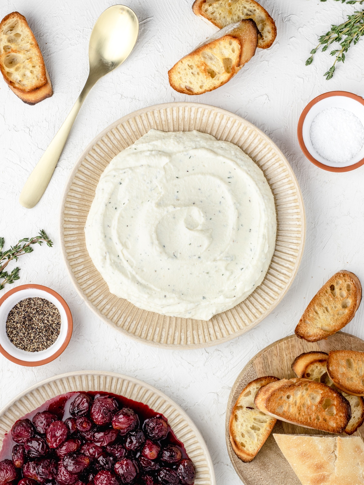 Ricotta Dip on a plate surrounded by roasted grapes and toasted baguette slices.