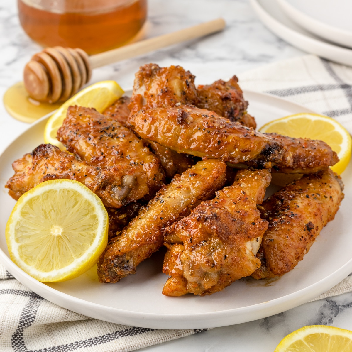 Quick and easy Honey Lemon Pepper wings with sliced lemons and hot honey for a drizzle.
