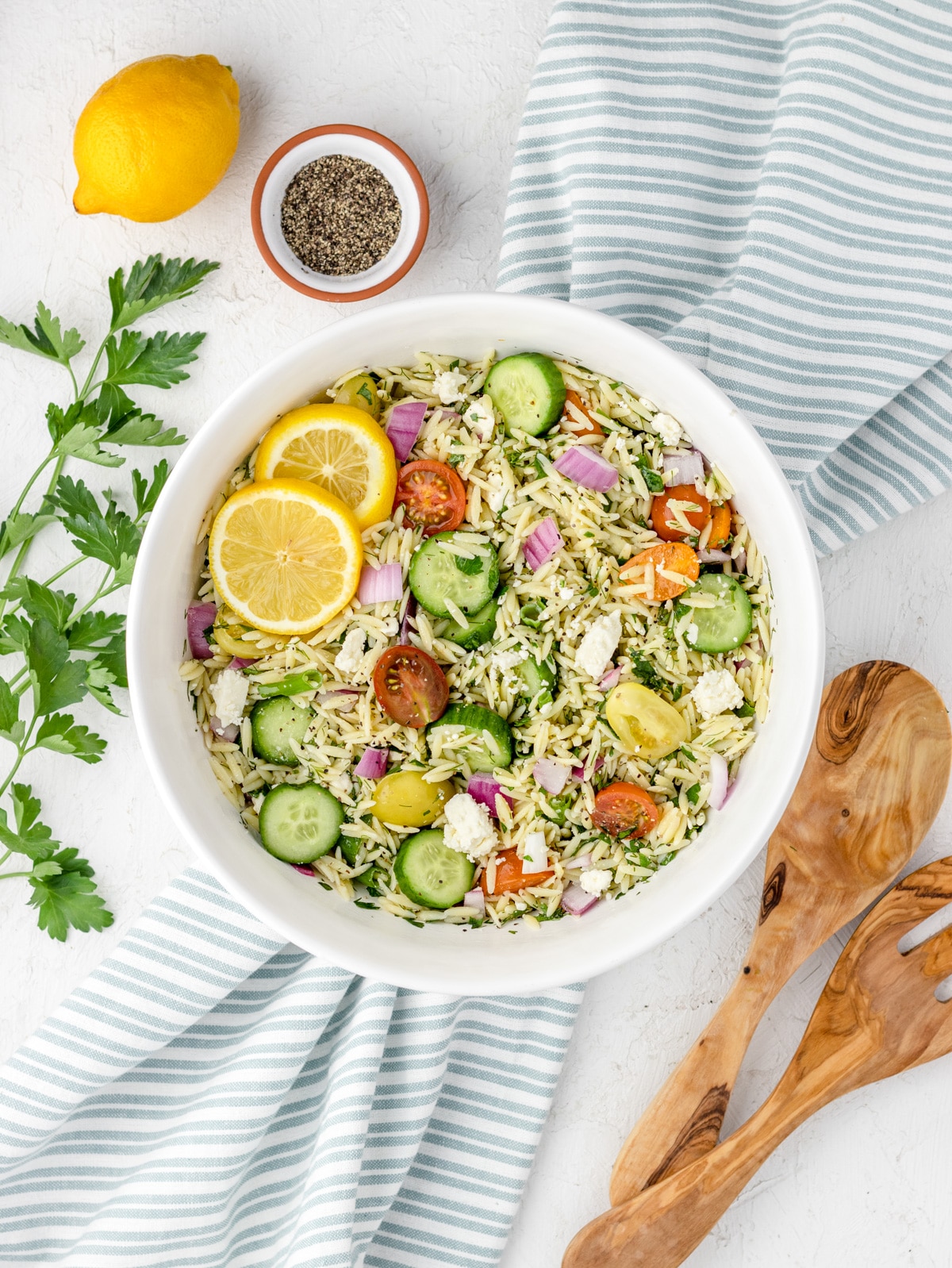Lemon Orzo Salad with feta and toppings mixed with dressing made of lemon juice, lemon zest, olive oil, salt, and black pepper.