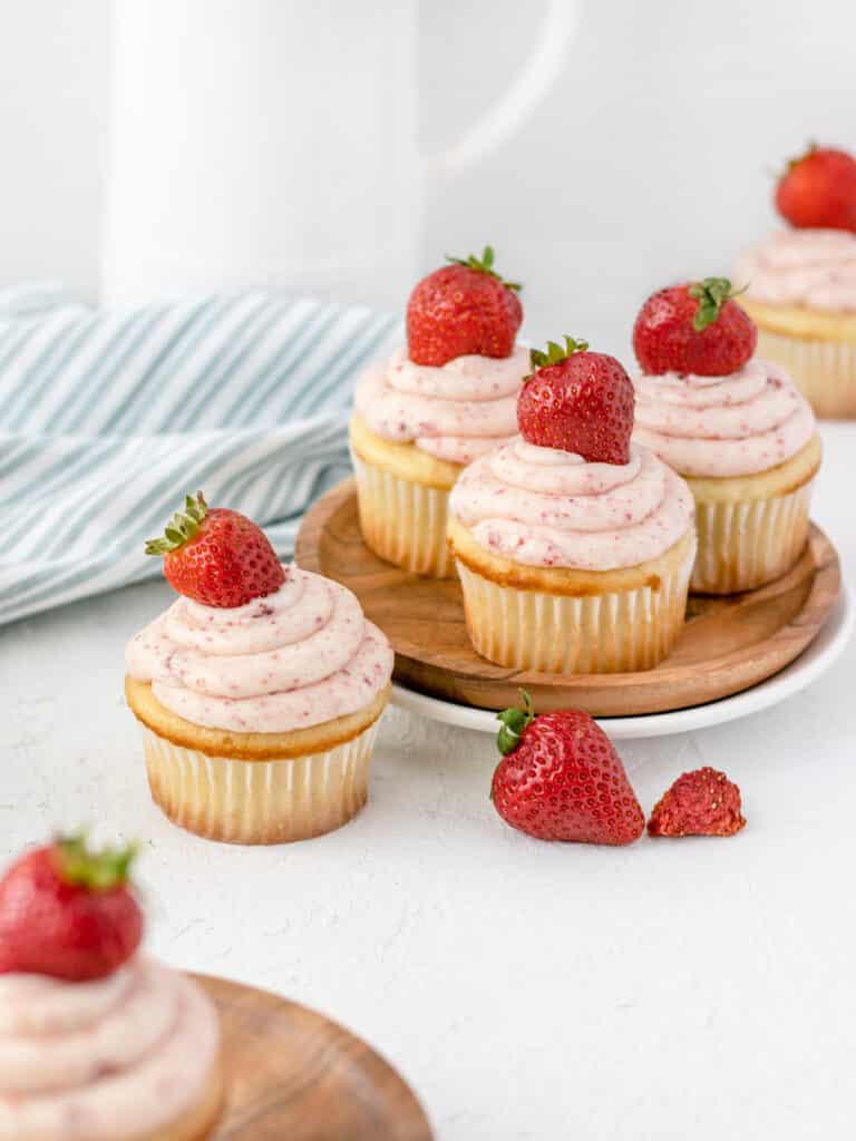 Strawberry Filled Cupcakes garnished with a strawberry buttercream and a fresh strawberry.