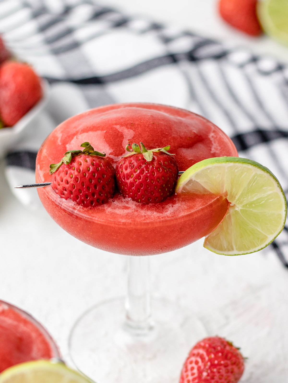 Close up of Strawberry Daiquiri Mocktail garnishes, two small strawberries and a lime slice.