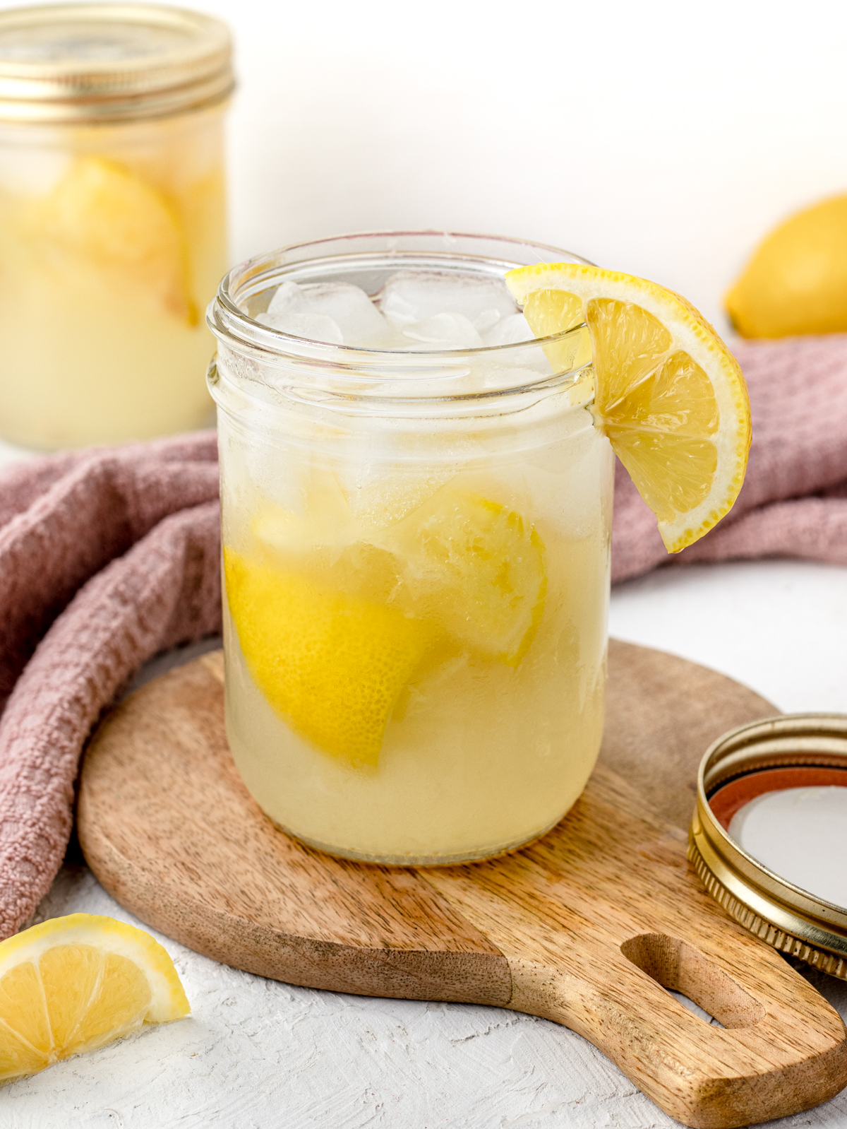 State Fair Lemonade with ice, lemons, and jar lid on the side.