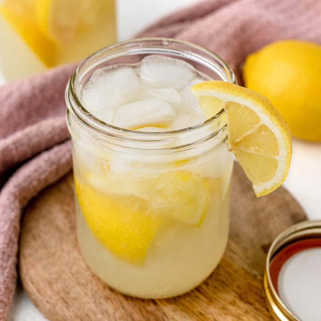 A full jar of iced, State Fair Lemonade and garnished with a lemon wedge.