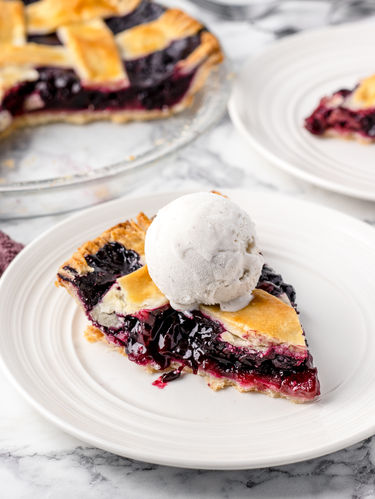 Strawberry Blueberry Pie with ice cream scooped on top.