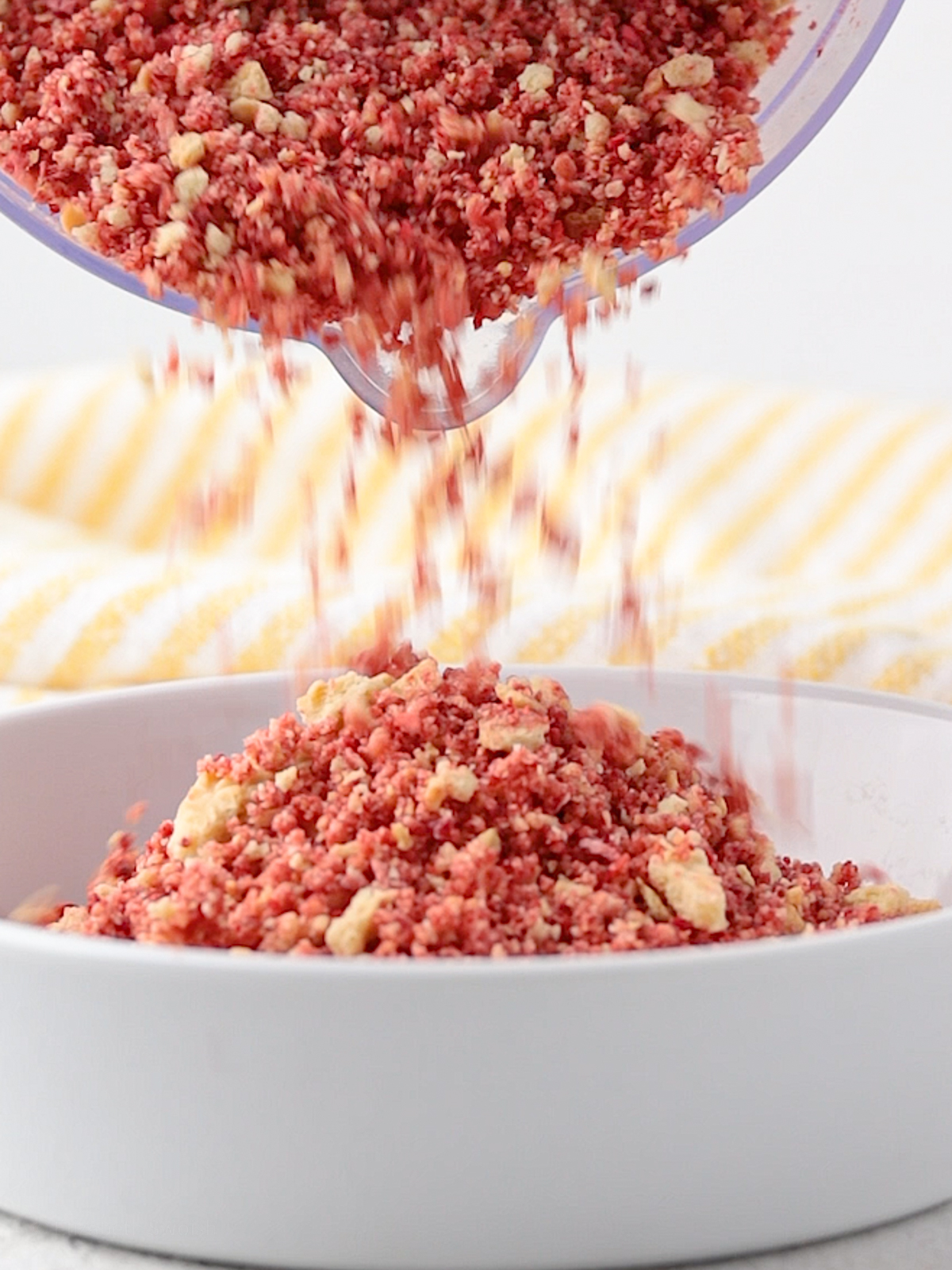 Pouring Strawberry Crunch Crumble into a dish.