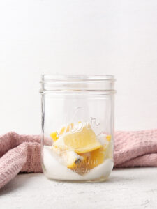 Jar filled with lemon wedges, and granular sugar.