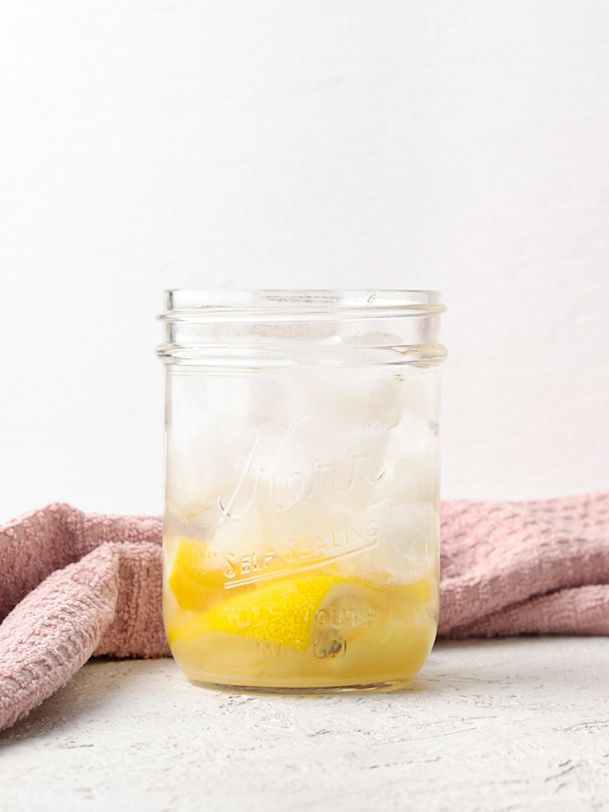 Jar filled with muddled lemon wedges and granular sugar, filled with ice, and topped with water. Before Shaking.