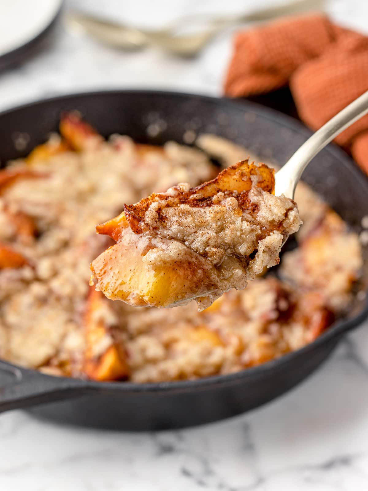 Bite of Smoked Peach Cobbler on a spoon.