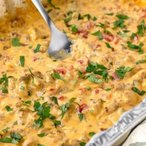 Cheesy Smoked Queso Dip in a pan with a spoon ready to scoop out.