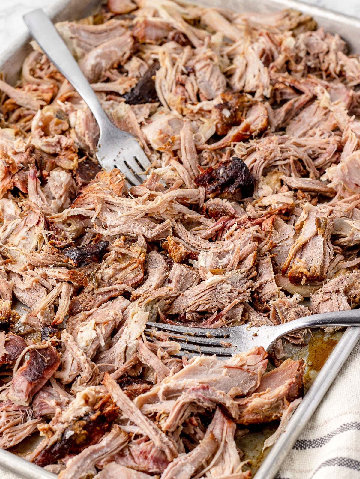 Shredded and pulled smoked pork butt on a pan with two forks.