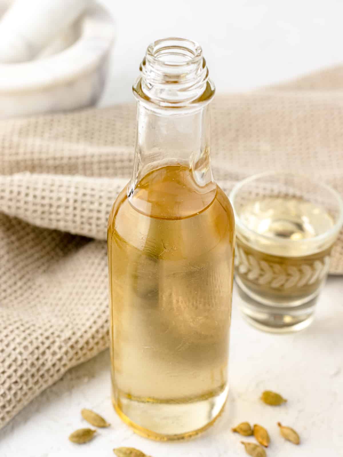 Cardamom Syrup in a glass bottle with a shot of the simple syrup next to it.