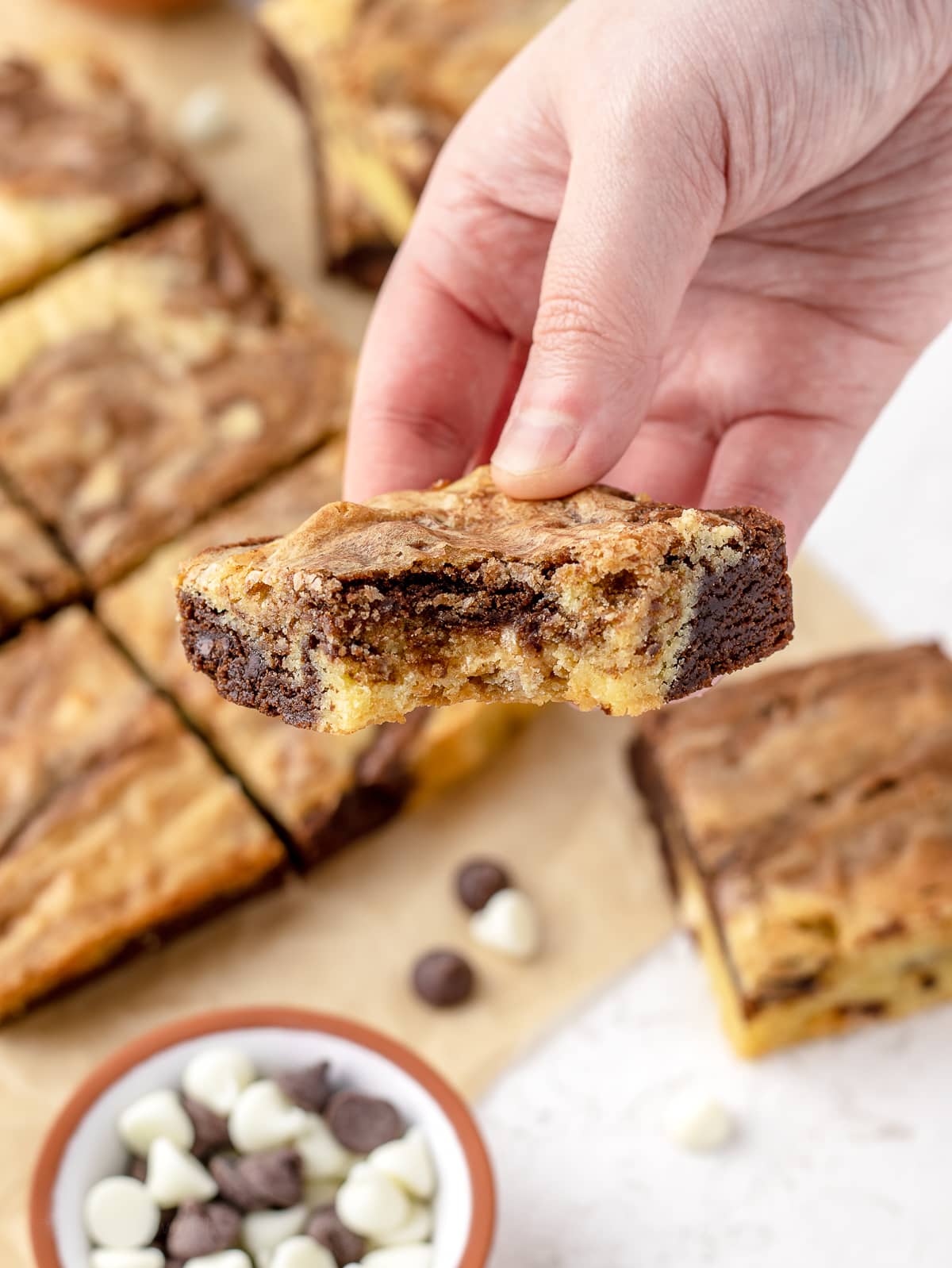 Hand holding a Brownie Blondie to see the swirls of flavor and chocolate chips.