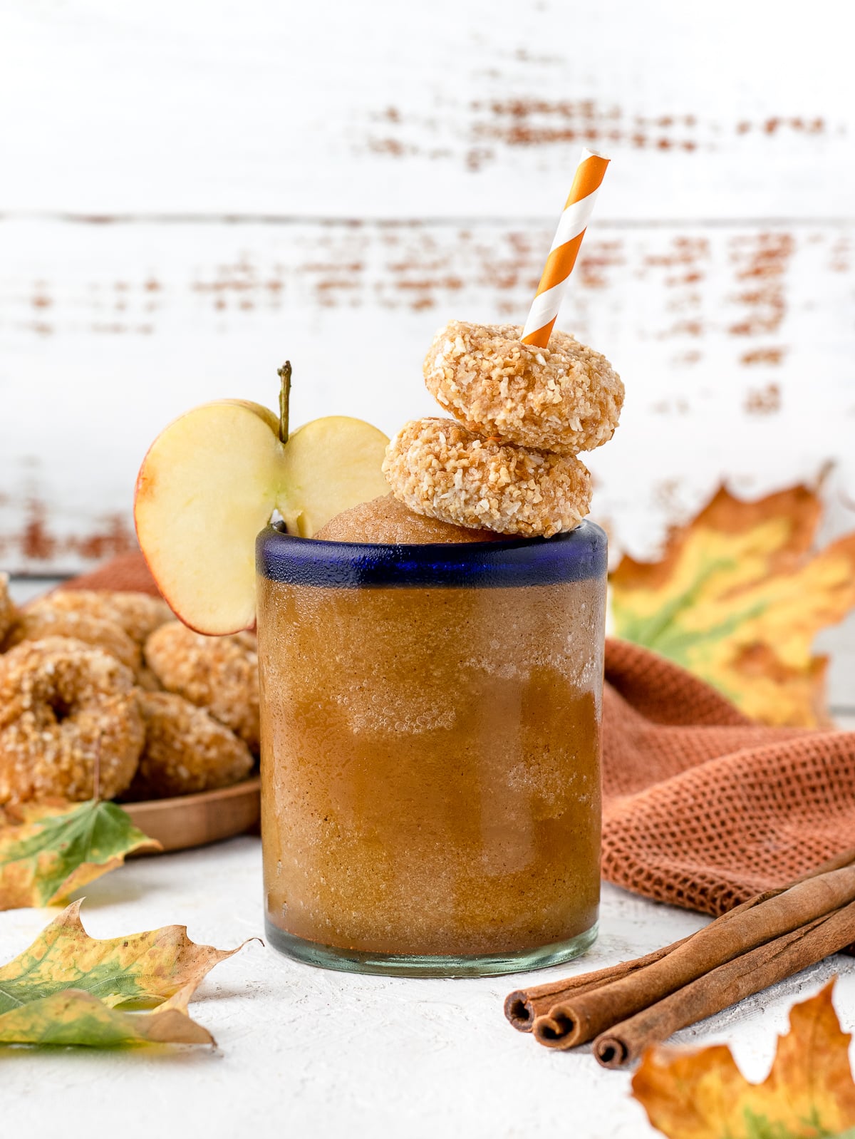 Glass of Apple Cider Slush garnished with an apple slice and two mini donuts.
