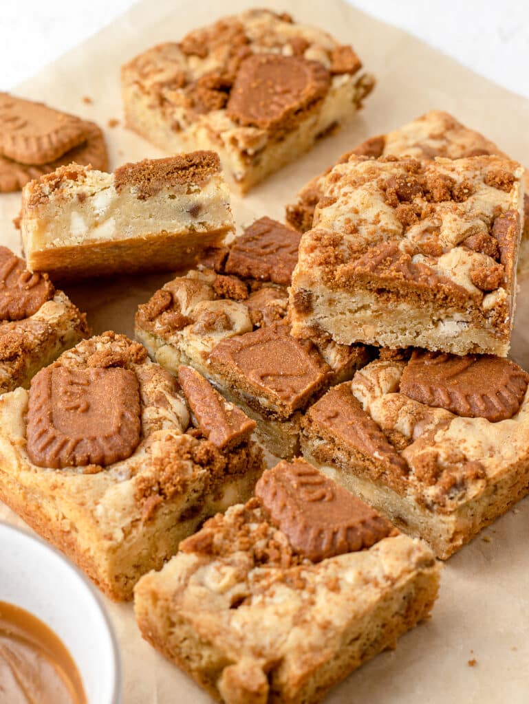 Close up of blondies texture and view of white chocolate, Biscoff cookies, and cookie butter on the side.