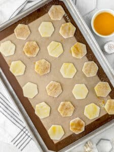 Pie Crust Cookies on a baking sheet slathered with egg wash and half with cinnamon sugar. Ready to go into the oven.