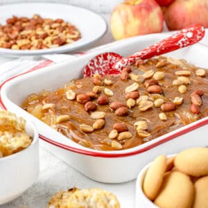 Caramel Apple Pie Dip served with a red enamel spoon ready to serve. Dippers and more peanuts on the side.