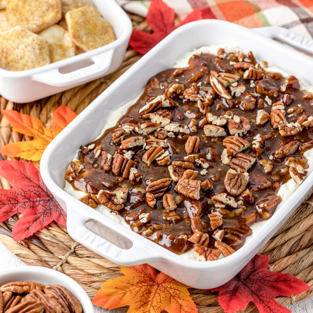 Pecan Pie Dip surrounded by pie crust chips, pecans, fall leaves.
