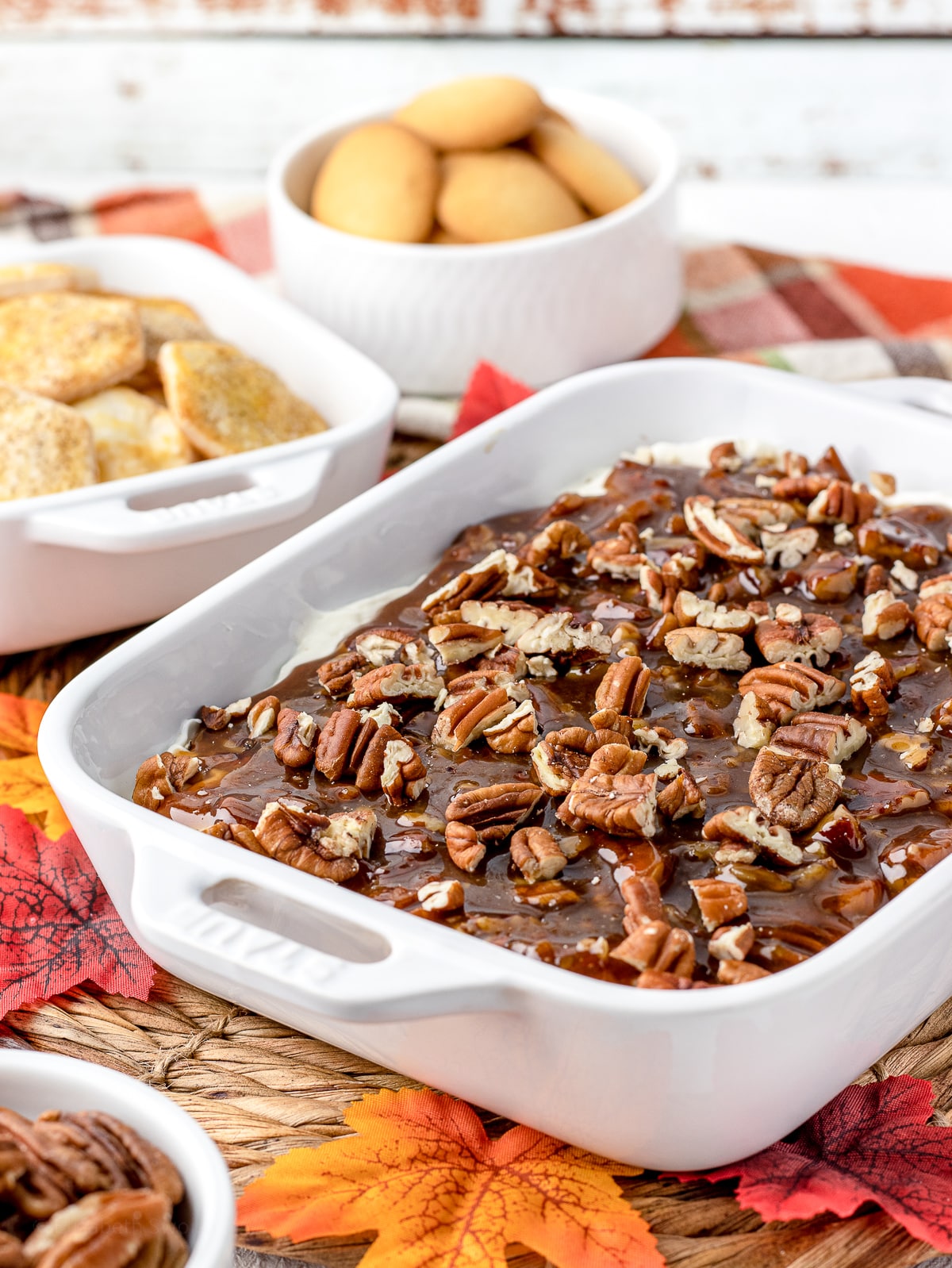 Pecan Pie Dip surrounded by pie crust chips, Nilla wafers, pecans, fall leaves.