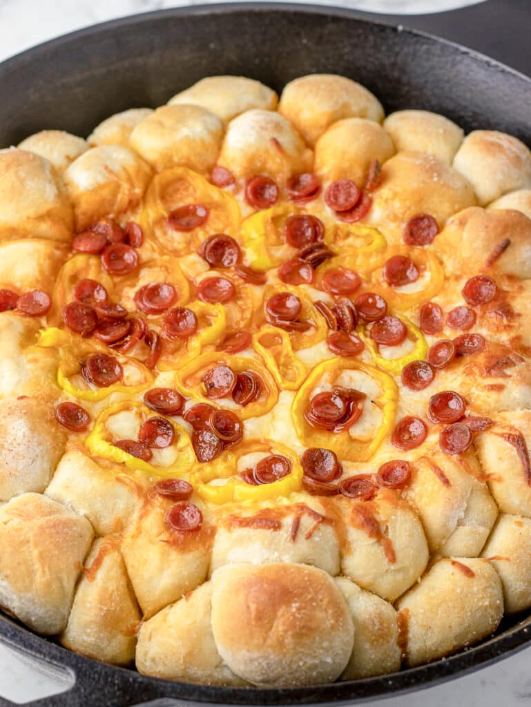 Baked Pizza Dip with Pizza Dough Balls in a cast iron skillet with honey drizzled over the top.