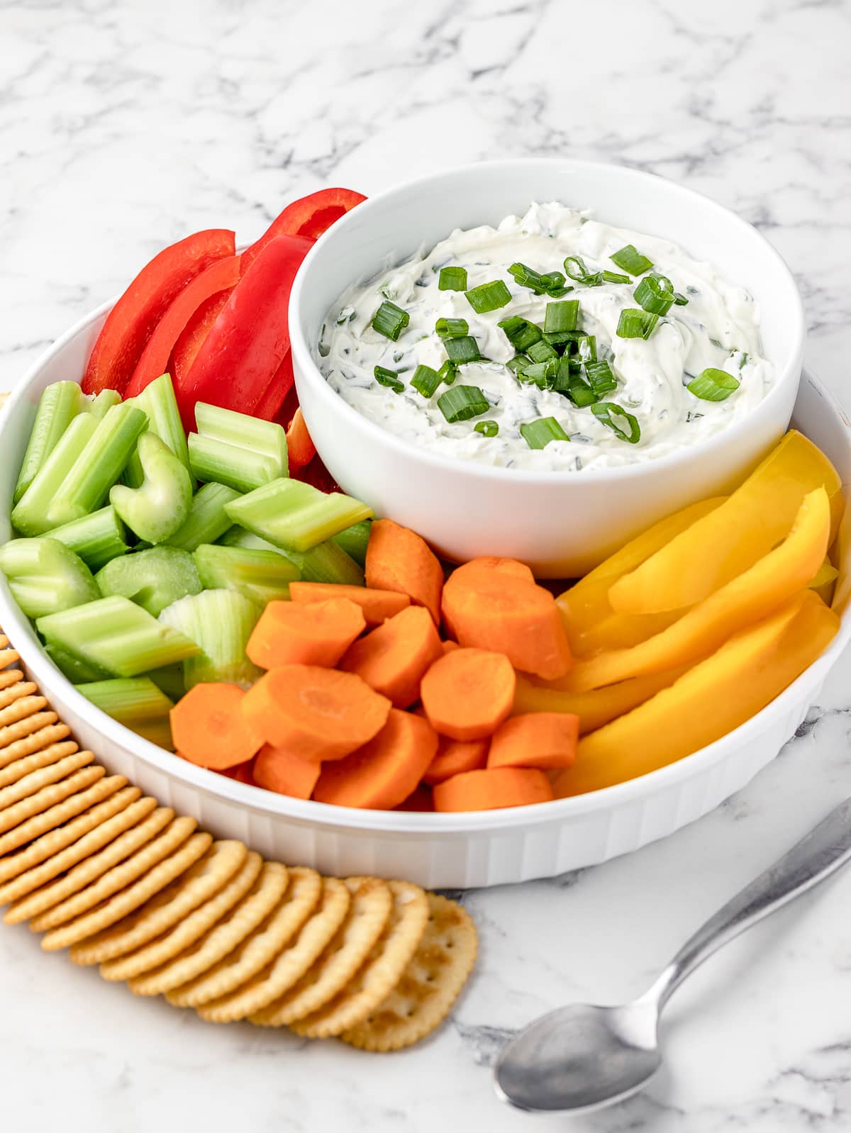 Green Onion Dip surrounded by fresh veggies and butter crackers.
