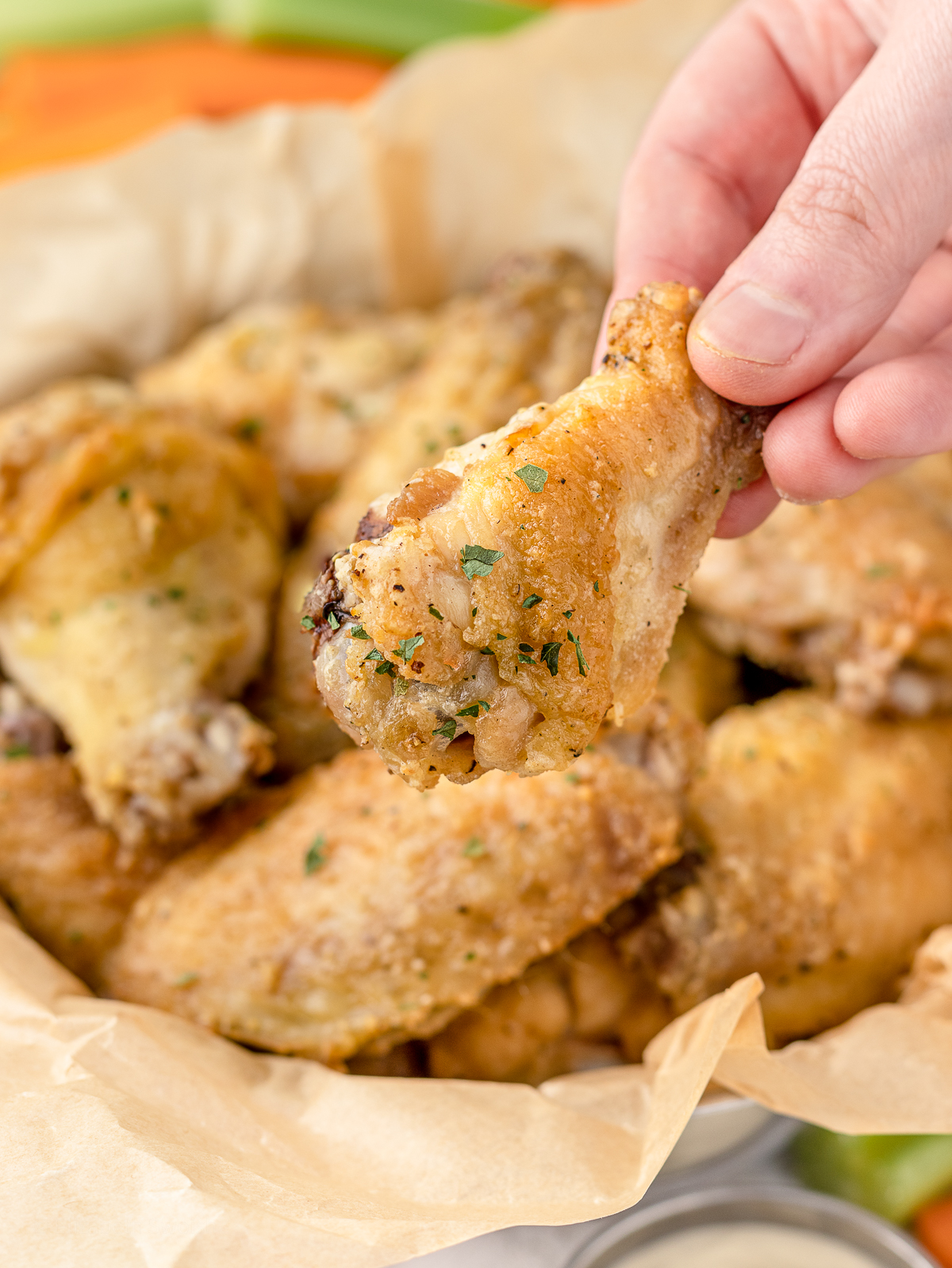 Hand holding chicken wing and ready to dip in sauce.