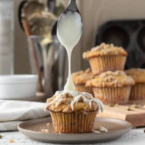 Coffee Cake Muffin on a plate with glaze dripping from a spoon onto the muffin.