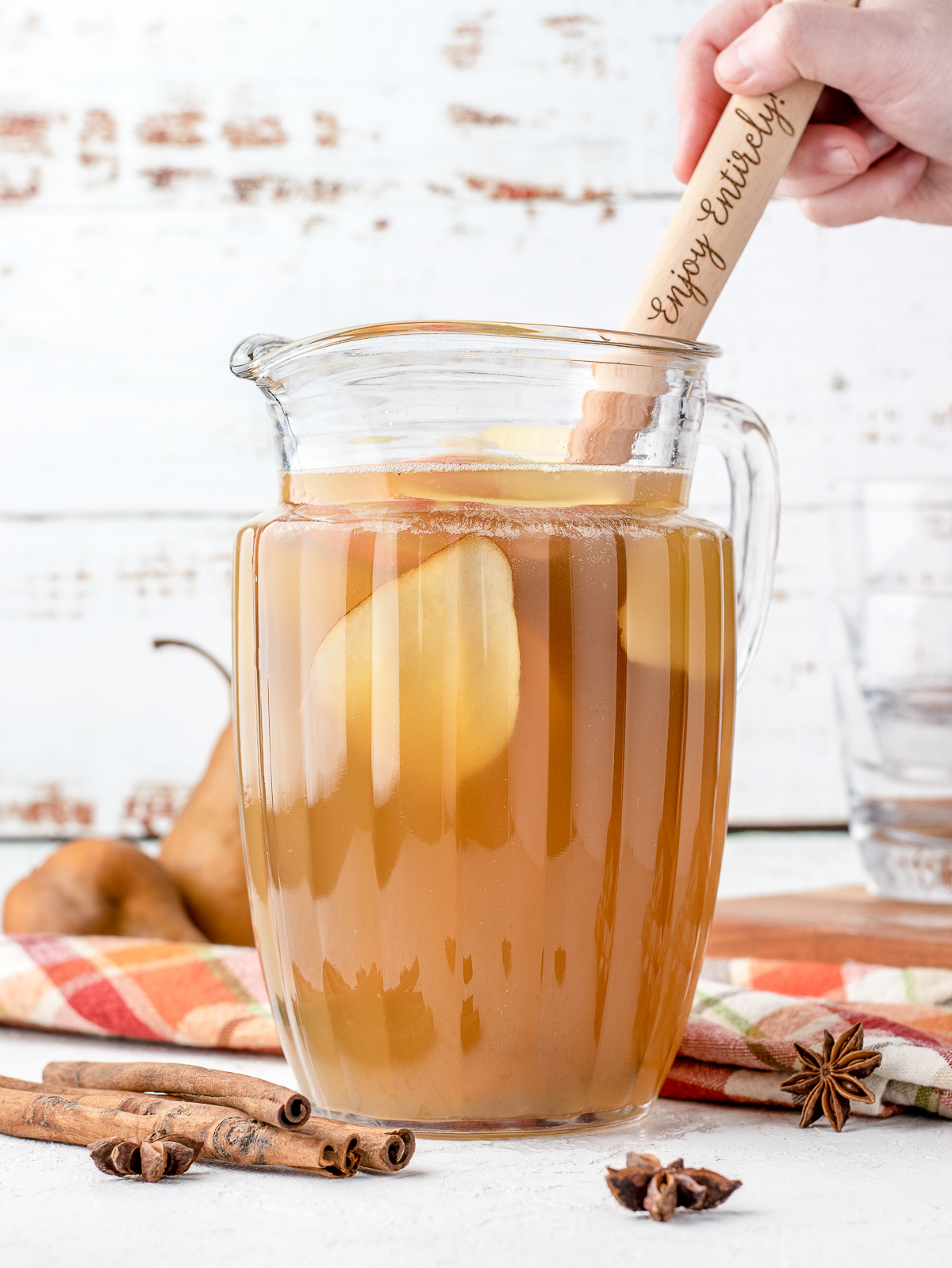 Hand stirring Apple Cider Sangria Mocktail with wooden spoon.