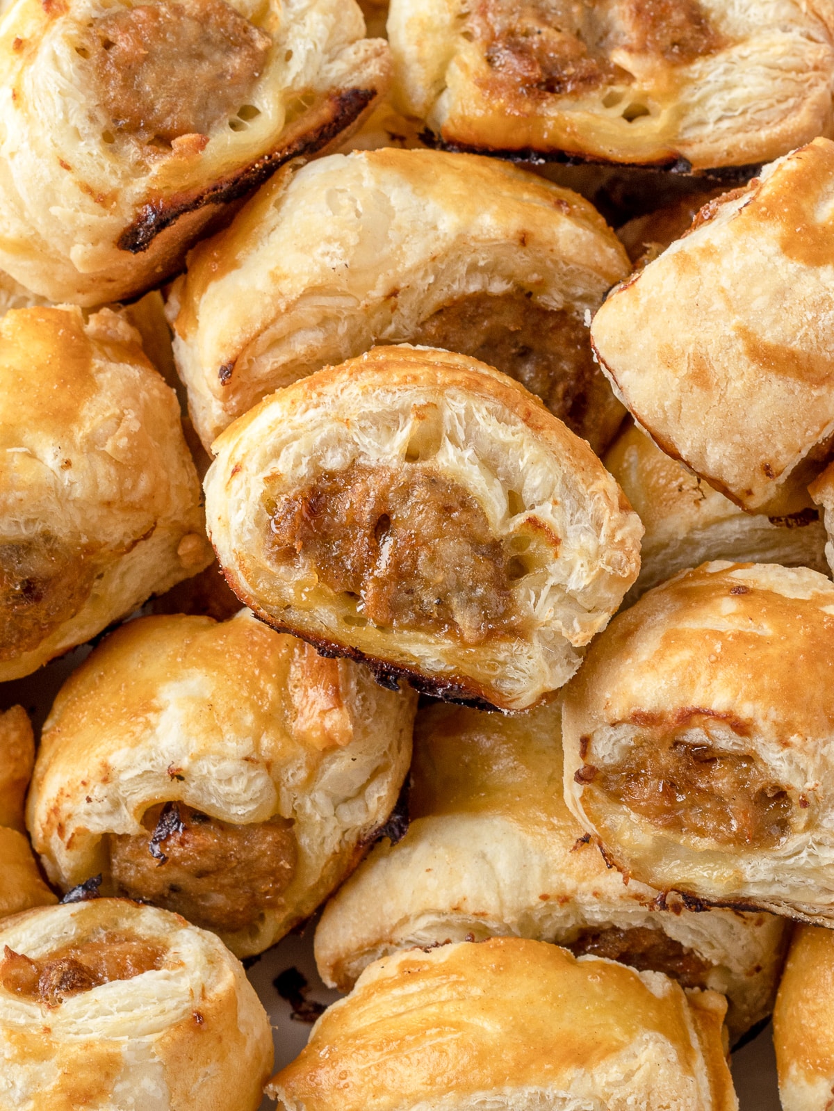 Close up of the flaky layers and chicken filling on a baked chicken sausage roll.