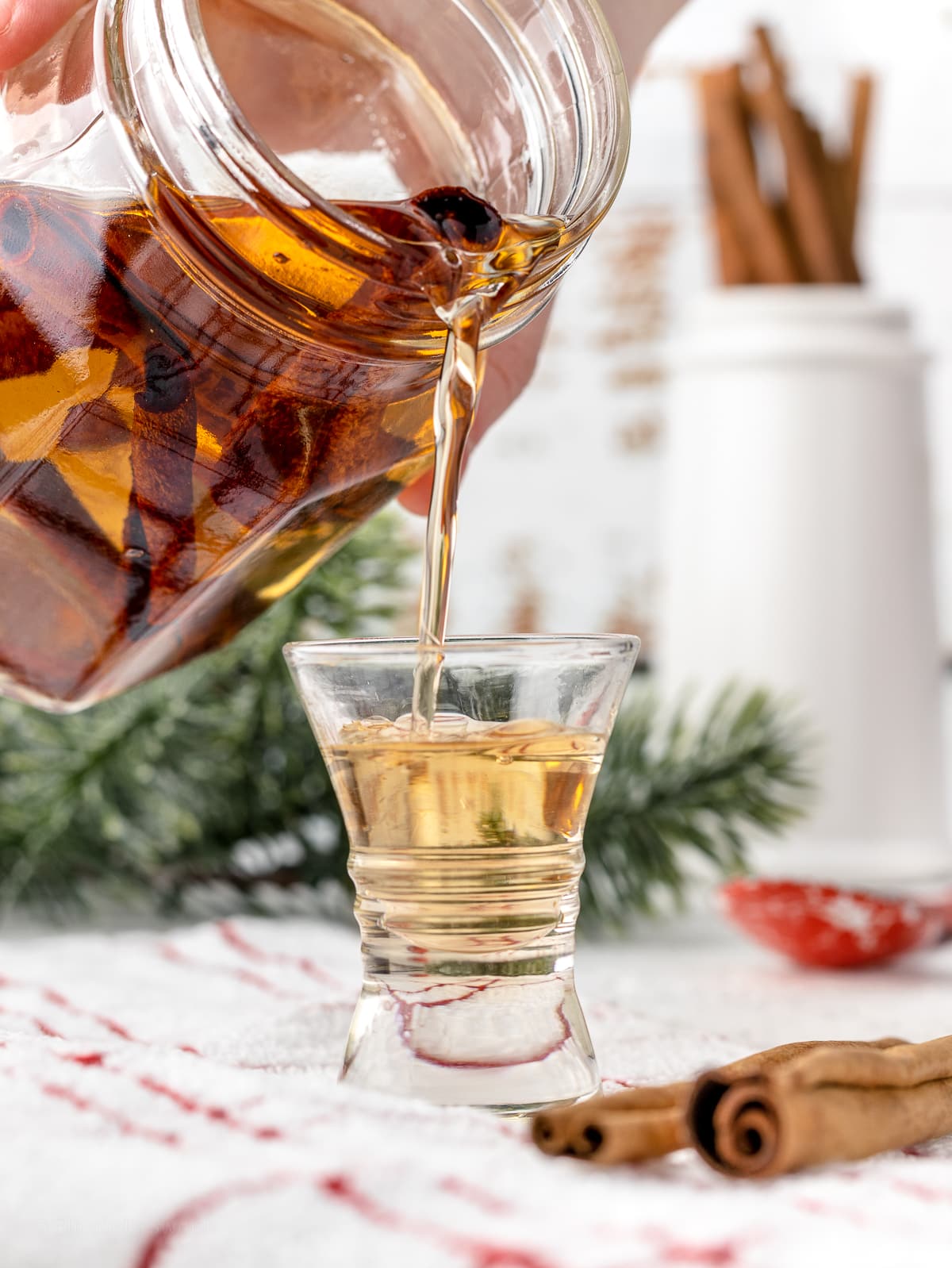Pouring Cinnamon Simple Syrup into a small shot glass.