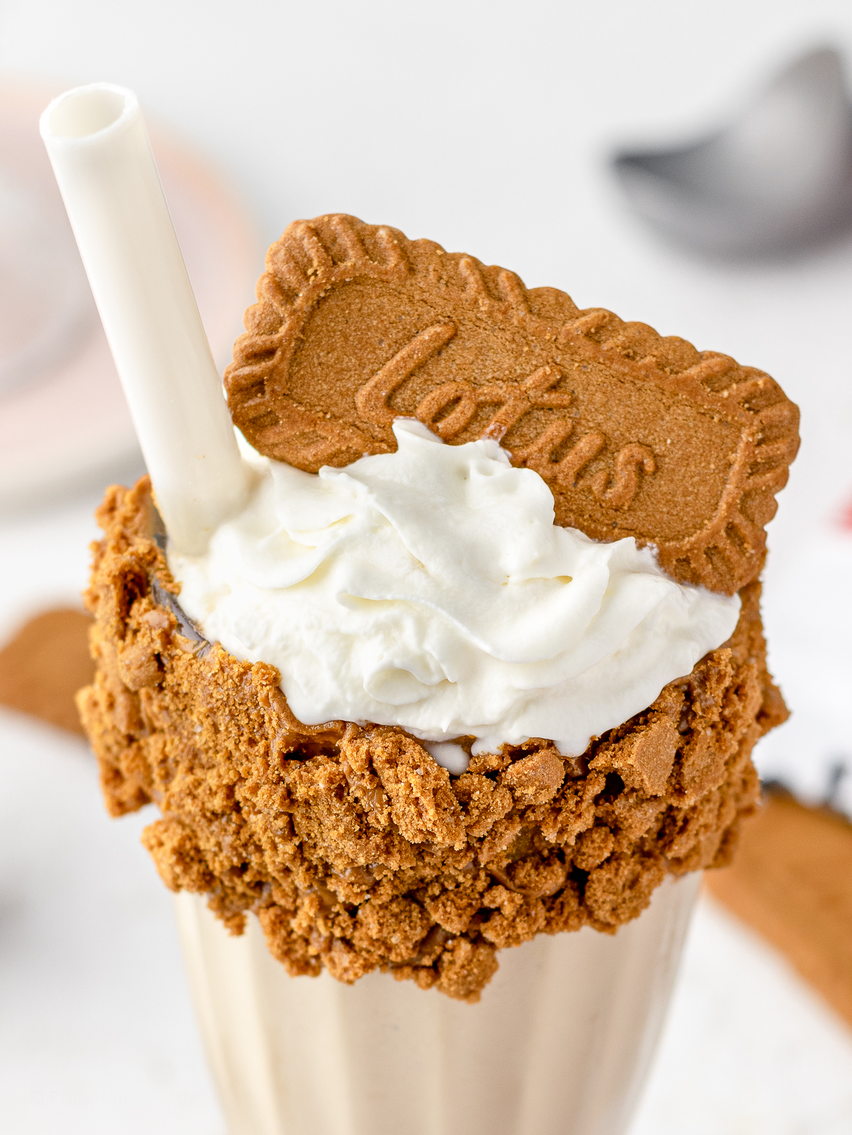 Close up of Lotus Biscoff cookie on top of a milkshake.