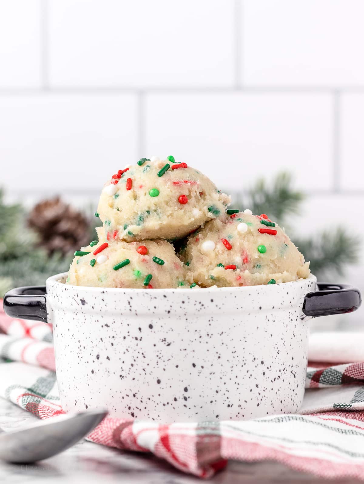Edible Cookie Dough in a handled bowl with a spoon on the side.