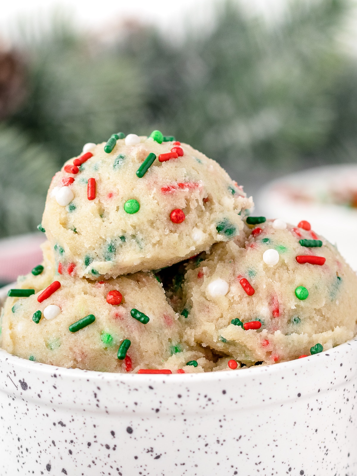 Close up of scoops of edible cookie dough to see red, green, and white sprinkles.