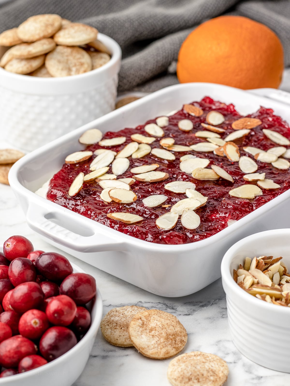 Pie Dip surrounded by Pie Crust Cookie Chips, fresh cranberries, an orange, and more slivered almonds.