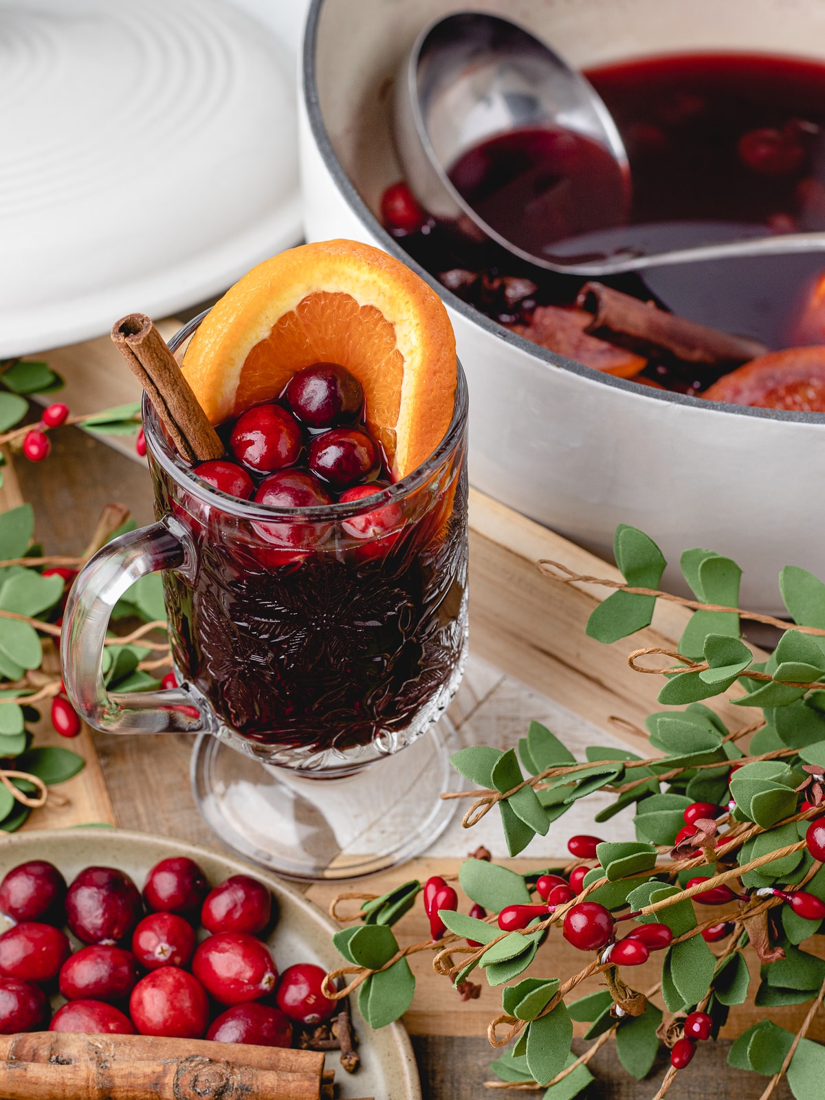 mulled wine in a glass and Dutch oven with more mulled wine and a metal ladle for serving.