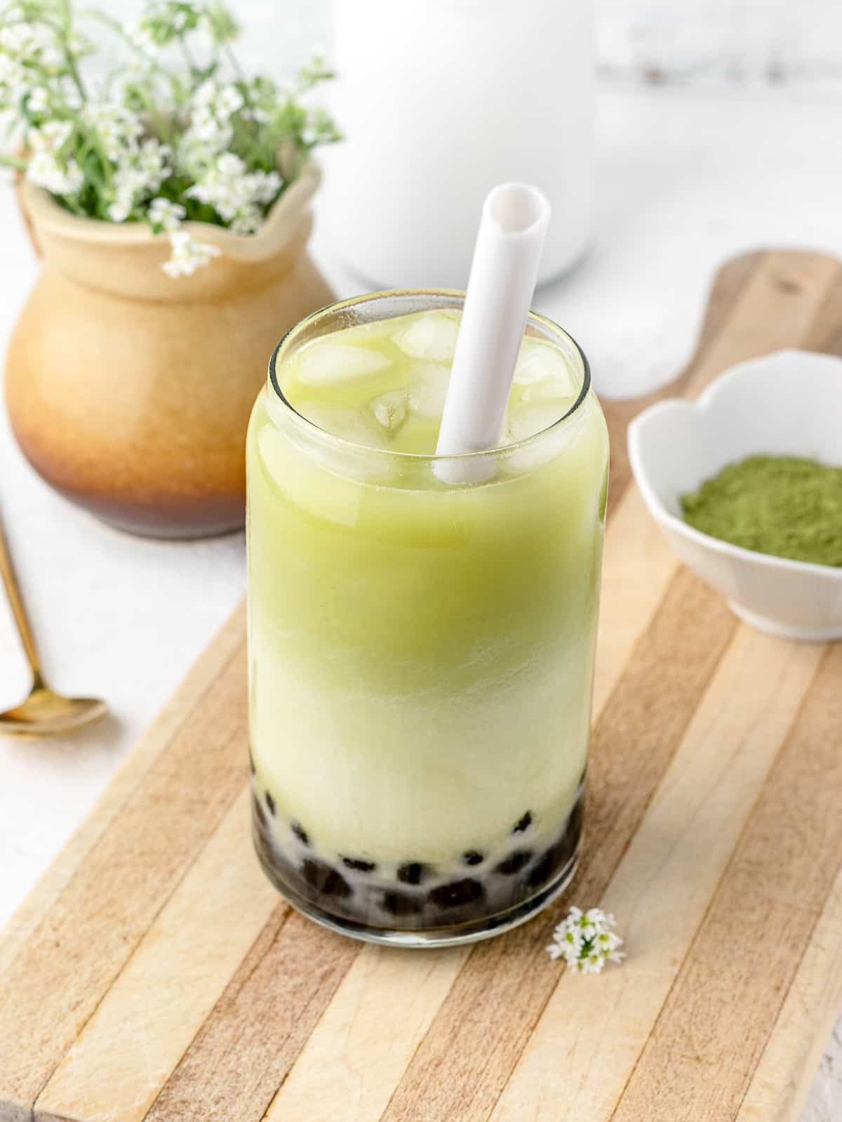 Layers of boba, matcha tea, and half and half in a glass.